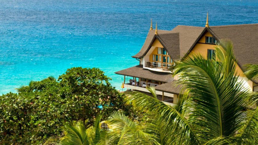 Exterior of Patatran Village Hotel, La Digue with ocean in the background | Just Seychelles