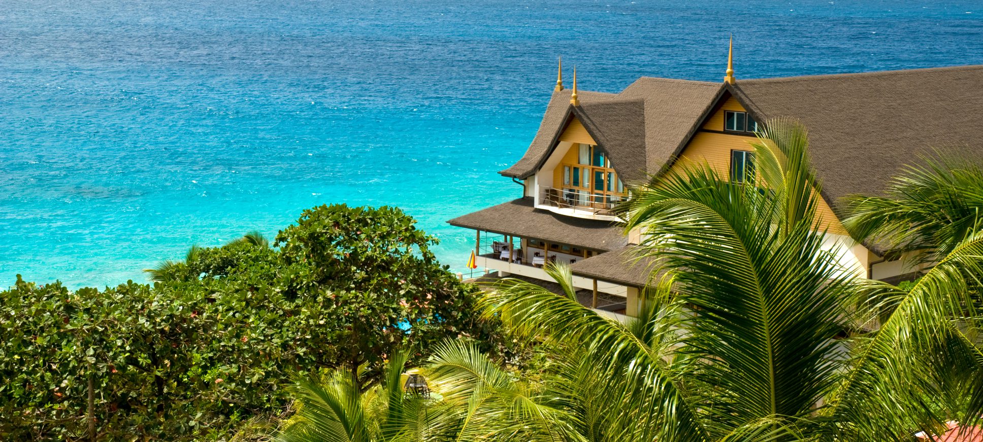 Exterior of Patatran Village Hotel, La Digue with ocean in the background | Just Seychelles
